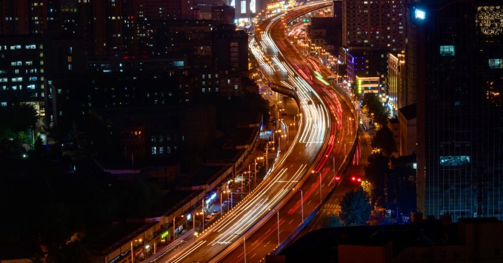 Dramatic cityscape at night with vibrant light trails on a highway, showcasing urban life.
